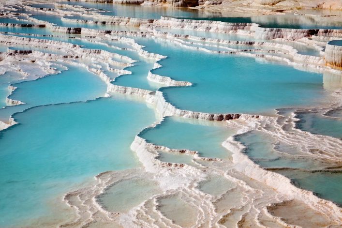 Türkisfarbene Thermalwasserbecken terrassenartig aneinandergereiht in Pamukkale, Türkische Ägäis, umgeben von weißen Kalksteinablagerungen.