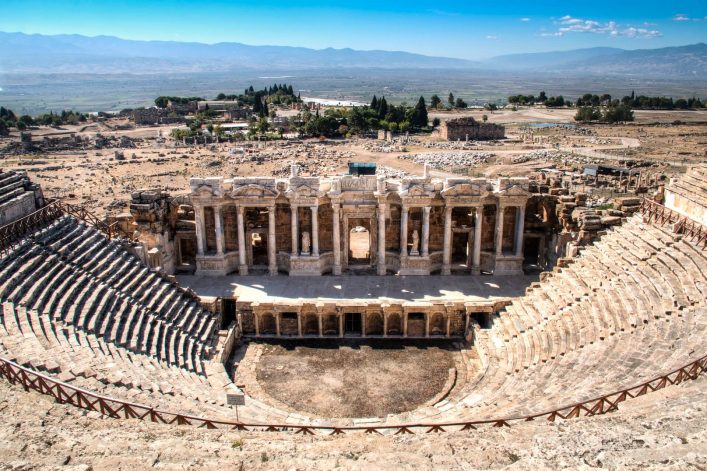 Antikes Theater von Hierapolis in der Türkischen Ägäis, halbkreisförmige Sitzreihen um eine Bühnenruine unter blauem Himmel.