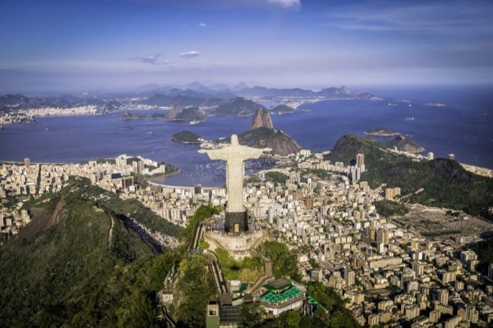 Luftaufnahme von Rio de Janeiro mit der berühmten Christus-Erlöser-Statue im Vordergrund, die die ausgedehnte Stadt und die Botafogo-Bucht überblickt, ein beliebtestes Ziel auf Kreuzfahrtrouten in Südamerika.