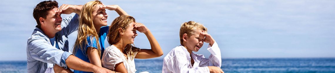 Familie mit Kindern am Strand schaut aufs Meer