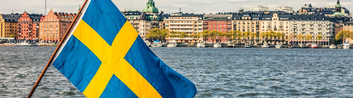 Blick auf die schwedische Innenstadt Stockholm und Flagge am Wasser