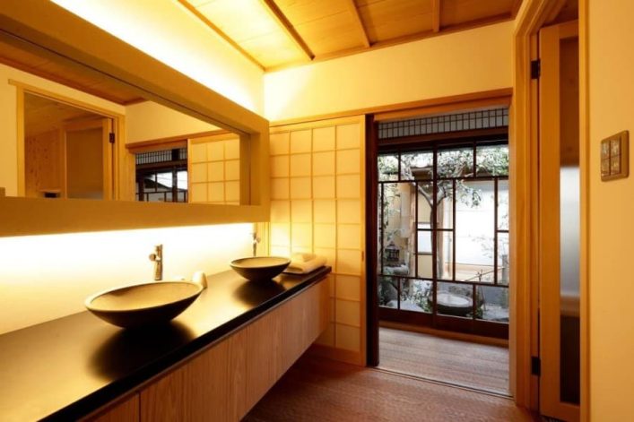 Gemütliches Ferienapartment im traditionell japanischen Stil in der ehemaligen Hauptstadt Kyoto. Zu sehen ist das Badezimmer des Apartments mit Blick in den typischen kleinen Innenhof. Ein Mix aus moderner Einrichtung und klassischen japanischen Elementen, wie Holz-Schiebetüren.