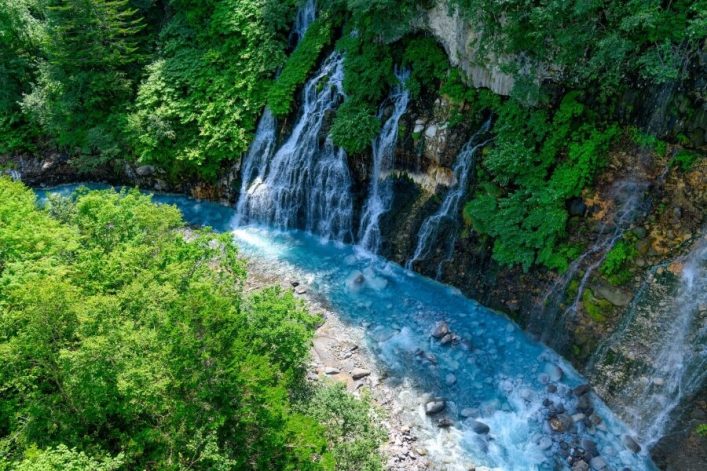 Türkises Wasser am Wasserfall Shirahige Waterfalls in Biei auf Hokkaido in Japan.