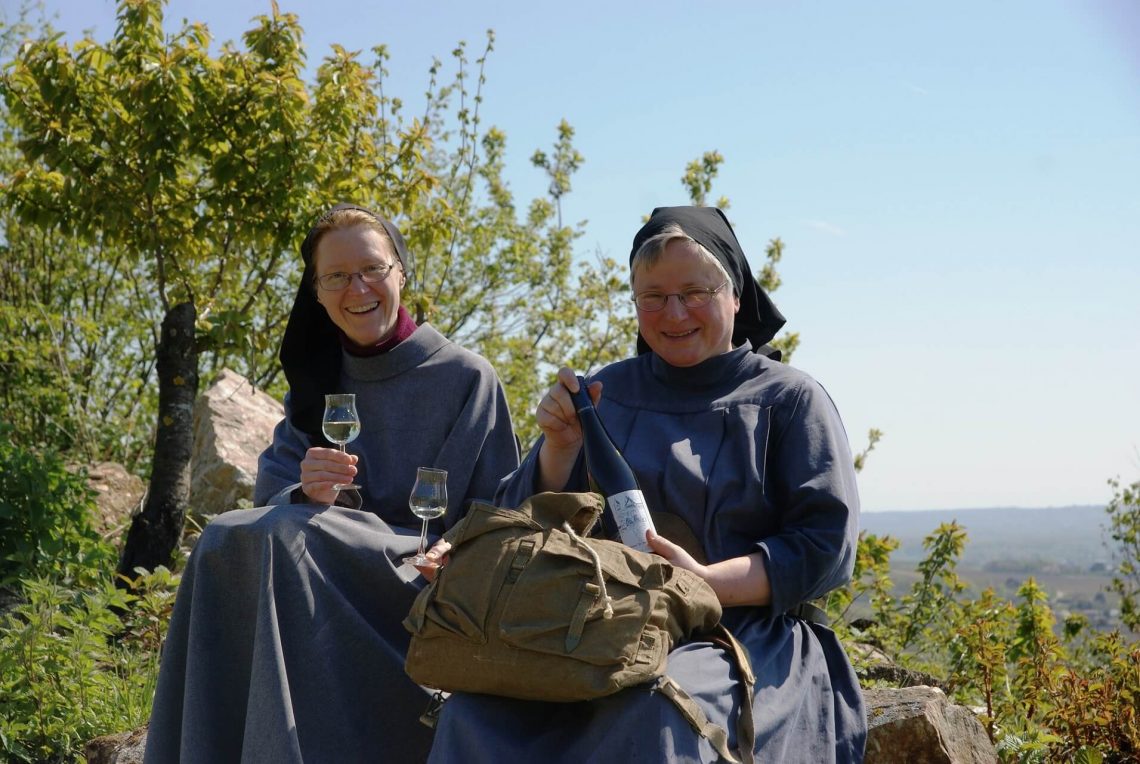 Benediktinerinnen sitzen mit Wein in den Weinbergen im Rheingau.