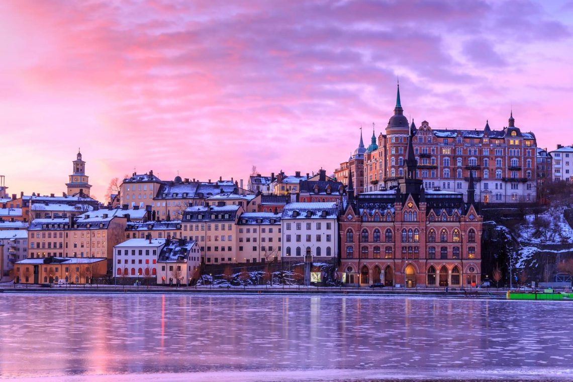 Sonnenuntergang auf Södermalm in Stockholm, Schweden. Der Himmel über einer süßen Stadt direkt am Wasser leuchtet rosa und lila.