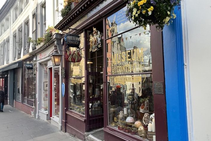 Auf einer belebten Straße in Edinburgh befinden sich historische Gebäude. Ein Geschäft namens