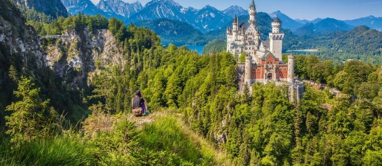 Das Schloss Neuschwanstein thront über dem See und ist umgeben von sattgrünen Wald.