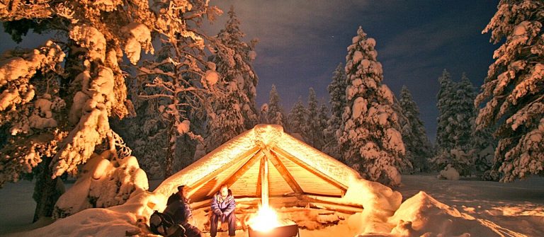 Schnee vor einer Hütte in Lappland und Lagerfeuer