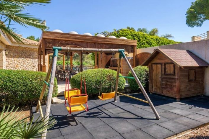 Im großzügigen Garten finden die kleinsten Gäste der Villa Casa del Pinaret einen zuckersüßen Kinderspielplatz samt Schaukeln und Holzhütte.