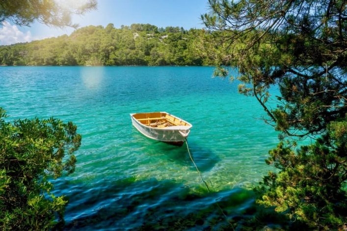 Eine malerische Sommerszene mit einem Ruderboot am Ufer des Veliko Jezero-Sees, im Nationalpark Mljet.